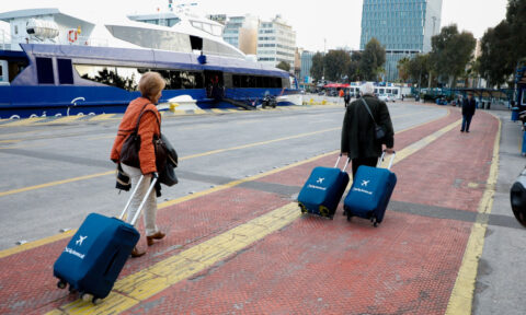 A couple of tourists with 3 suitcases walk at the port of piraeus